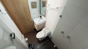 A compact bathroom with a toilet, sink, and mirror. - Exclusivo Apartamento en el Poblado by Hoost 705 (Medellín)