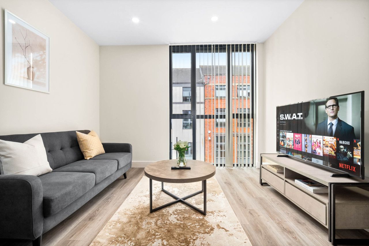 A modern living room with a grey sofa, a coffee table, and a TV displaying a Netflix interface.