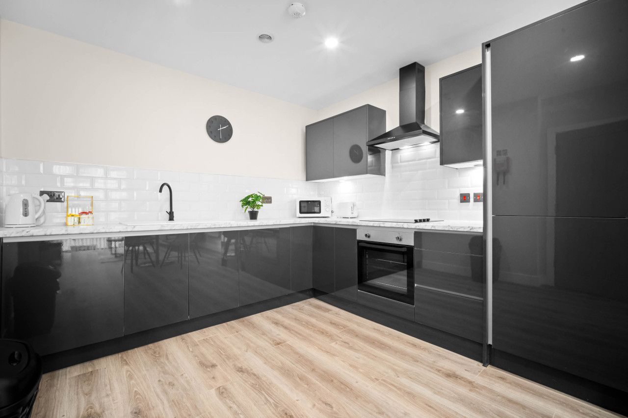 Cozinha moderna com armários pretos, micro-ondas, fogão e um relógio na parede.