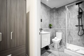 Un baño moderno con ducha, inodoro y lavamanos.