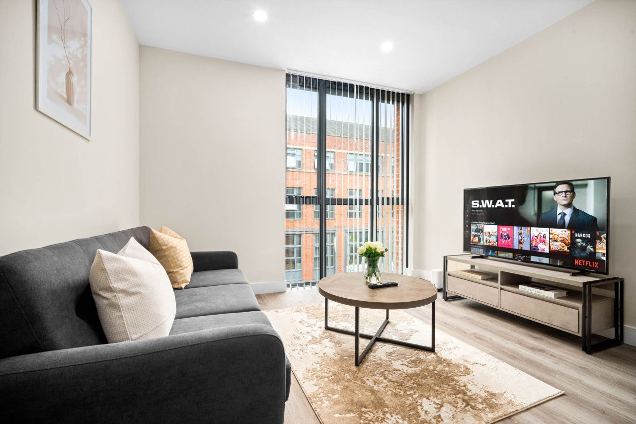 Una sala de estar moderna con un sofá gris, una mesa de centro y un televisor de pantalla plana mostrando la interfaz de Netflix.