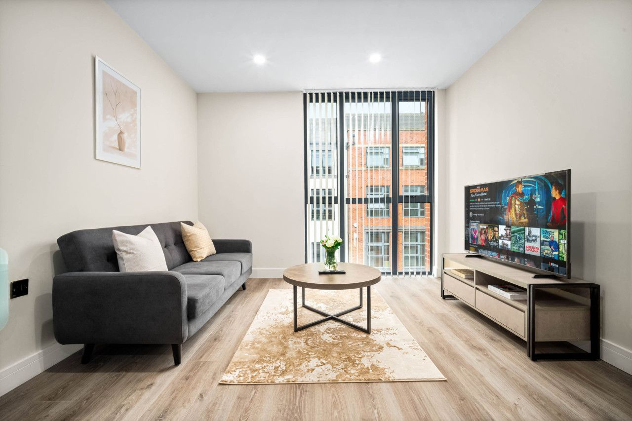 A modern living room with a grey sofa, a coffee table, and a TV on a wooden stand.