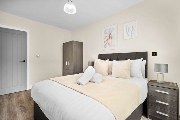 Een slaapkamer met een bed, nachtkastje, kledingkast en een deur.