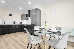 Una cocina moderna con comedor, que incluye una mesa de vidrio, sillas grises y un microondas negro.