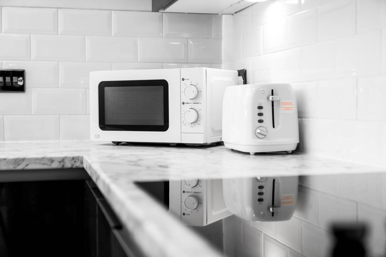 A kitchen with a microwave and toaster on a marble countertop.