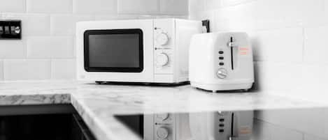 Una cocina con microondas y tostadora sobre una encimera de mármol.