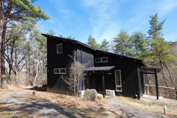 A black building with a sloped roof, large windows, and a covered porch area.