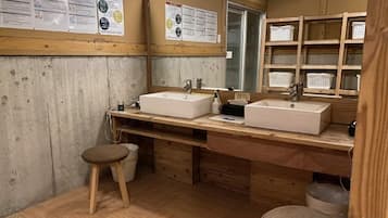 A bathroom with two sinks, wooden cabinets, a mirror, and a wooden stool.