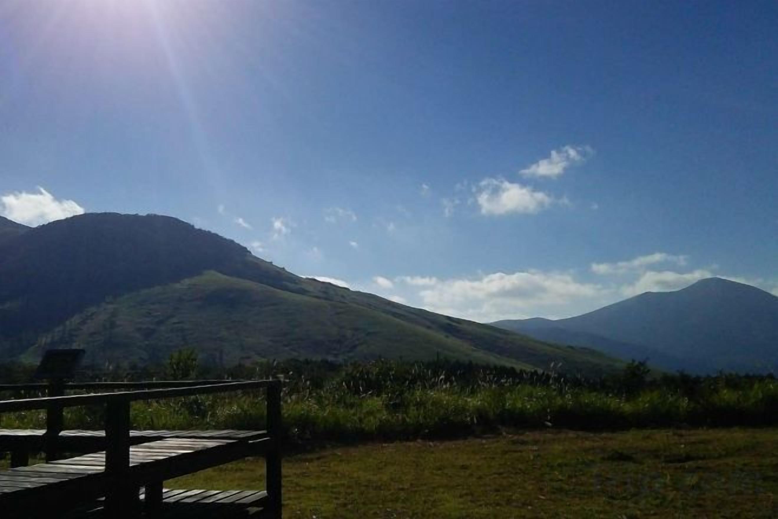 Un pontile di legno con vista su una catena montuosa sotto un cielo sereno.