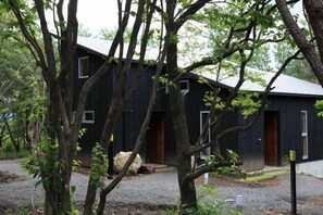 A rustic building with multiple windows and a door, surrounded by trees. - Lodge Toranoyu (Kokonoe)