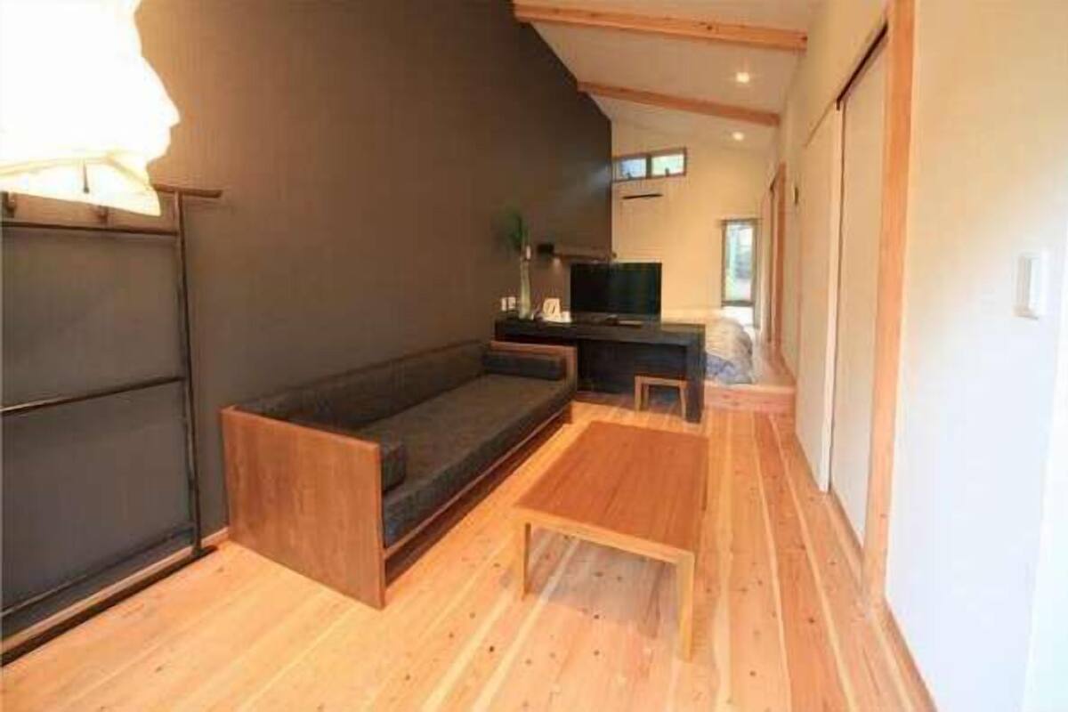 Une pièce avec un mur de couleur sombre, un plancher en bois, un canapé, une petite table et un téléviseur.