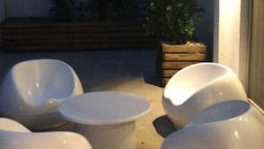 A modern outdoor seating area with white, bowl-shaped chairs and a bench. - Art House Carranza  (Buenos Aires)