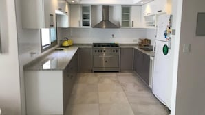 A modern kitchen with white cabinetry, a stainless steel stove, and a built-in oven. - Art House Carranza  (Buenos Aires)