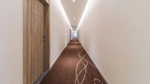 A narrow, well-lit hallway with a wooden door on the left and a carpeted floor. - HanTing Hotel (Guangzhou Tianhe Bus Station) (Guangzhou)