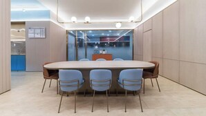 A modern conference room with a large oval table, six blue chairs, and a glass partition. - HanTing Hotel (Guangzhou Tianhe Bus Station) (Guangzhou)