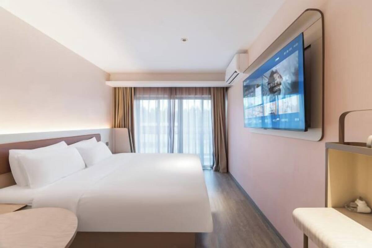 Une chambre d’hôtel équipée d’un lit, d’un bureau et d’un téléviseur fixé au mur.