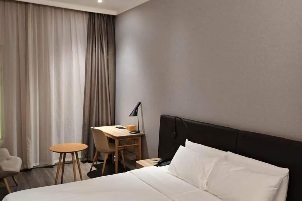 Une chambre d’hôtel avec un lit, un bureau, une chaise et une lampe.