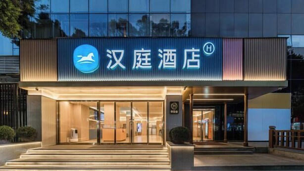 A hotel entrance with a modern design, featuring a prominent logo and a well-lit facade. - HanTing Hotel (Guangzhou Tianhe Bus Station) (Guangzhou)
