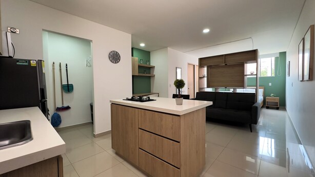 A modern kitchen with a central island, a dining area with a sofa, and a small side table. - Hermoso Apartamento en la mejor ubicacion by Hoost 610 (Medellín)