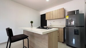 A modern kitchen with a central island, stainless steel refrigerator, and wooden cabinets. - Hermoso Apartamento en la mejor ubicacion by Hoost 610 (Medellín)