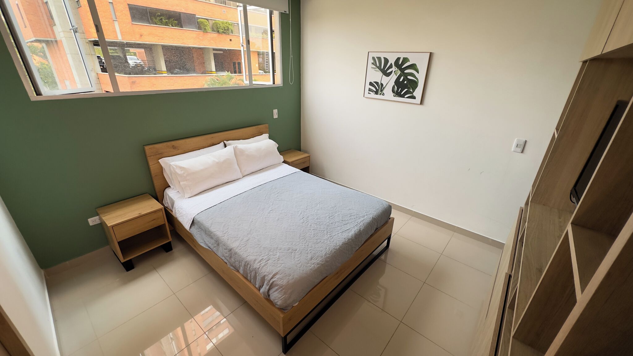 A bedroom with a bed, nightstands, a window, and a door.