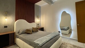 A modern bedroom with a large bed, wooden paneling, and a unique mirror design.