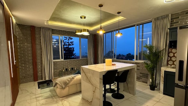 A modern kitchen with a marble countertop, pendant lighting, and a view of the outdoors.