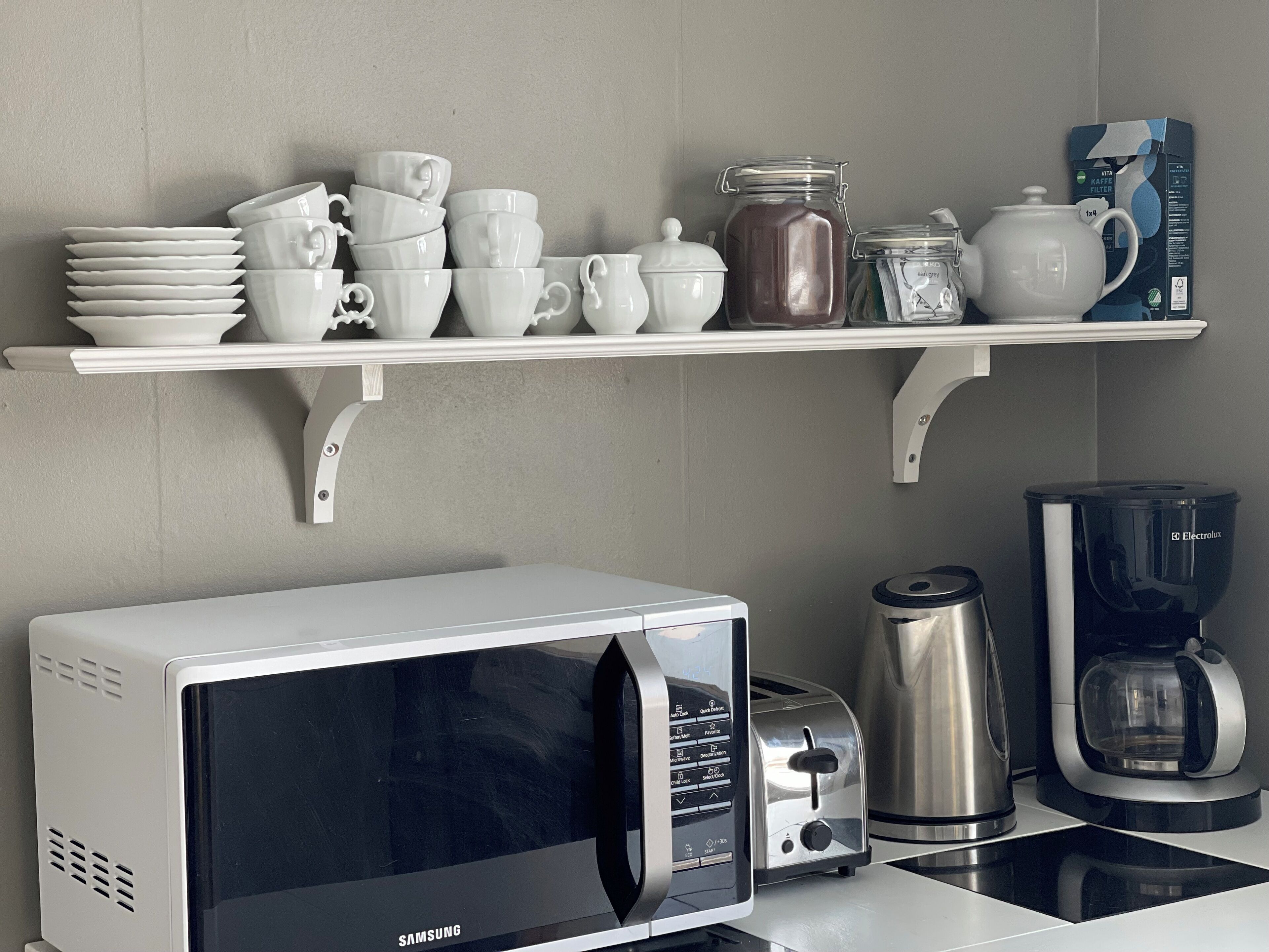 Une cuisine équipée d’un four à micro-ondes, d’un grille-pain, d’une bouilloire et d’une machine à café, le tout posé sur le plan de travail.