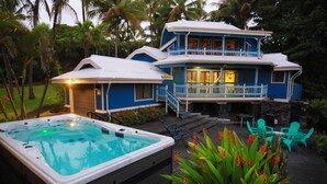 A two-story house with a hot tub and outdoor seating. - Kehena Black Sand Beach House - ocean view - swim spa (Pahoa)