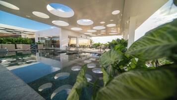 Un área interior de piscina moderna con tragaluces circulares, asientos de descanso y una entrada de puertas de vidrio.