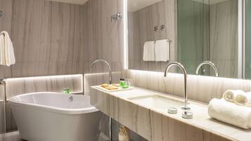 Un baño moderno con una bañera independiente, un tocador con espejo y un espejo grande sobre el lavabo.