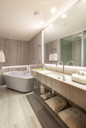 A modern bathroom with a freestanding bathtub, a vanity with a mirror, and a large mirror above the sink. - Mona Hotel (Teresina)