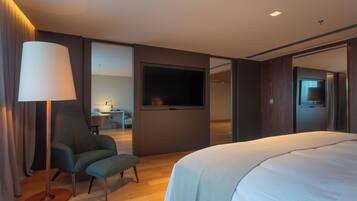 Habitación de hotel moderna con una cama grande, un escritorio, una silla, un televisor y una lámpara.