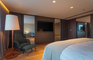 A modern hotel room with a large bed, a desk, a chair, a TV, and a lamp. - Mona Hotel (Teresina)