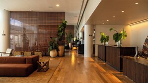 A modern lobby with a wooden reception desk, seating area with sofas, and potted plants. - Mona Hotel (Teresina)