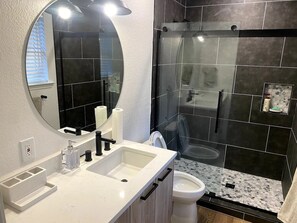 Een douche, handdoeken, shampoo, toiletpapier