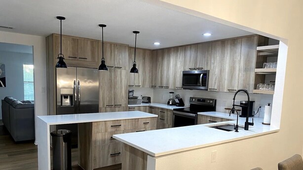 Una cocina moderna con una isla central, electrodomésticos de acero inoxidable y armarios de madera.