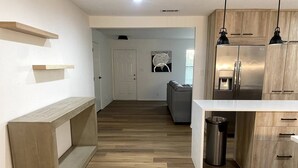 Una cocina moderna con armarios de madera, un refrigerador de acero inoxidable y una encimera blanca.