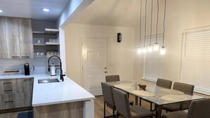 Una cocina moderna con encimera blanca, electrodomésticos de acero inoxidable y horno empotrado.