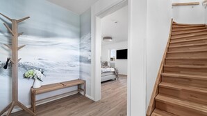 A modern interior with a wooden staircase, a bench, and a wall with a painting.