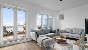 A modern living room with two grey sofas, a small coffee table, and a large window with a view of the city.