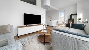 A modern living room with a flat-screen TV, a round wooden coffee table, and a sofa.