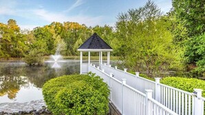 A gazebo with a white railing and a pond with a fountain in the background. - Step into Colonial Charm at The Historic Powhatan Resort in Williamsburg - 2 Bd. (Williamsburg)