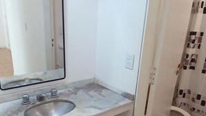 Une salle de bain avec un lavabo blanc, un miroir et des toilettes.