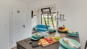 Een moderne keuken met een eettafel gedekt voor een maaltijd, met diverse soorten eten en een blauwe bank op de achtergrond.
