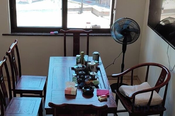 A dining area with a wooden table, chairs, and a fan.