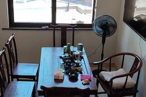Comedor con mesa de madera, sillas y un ventilador.