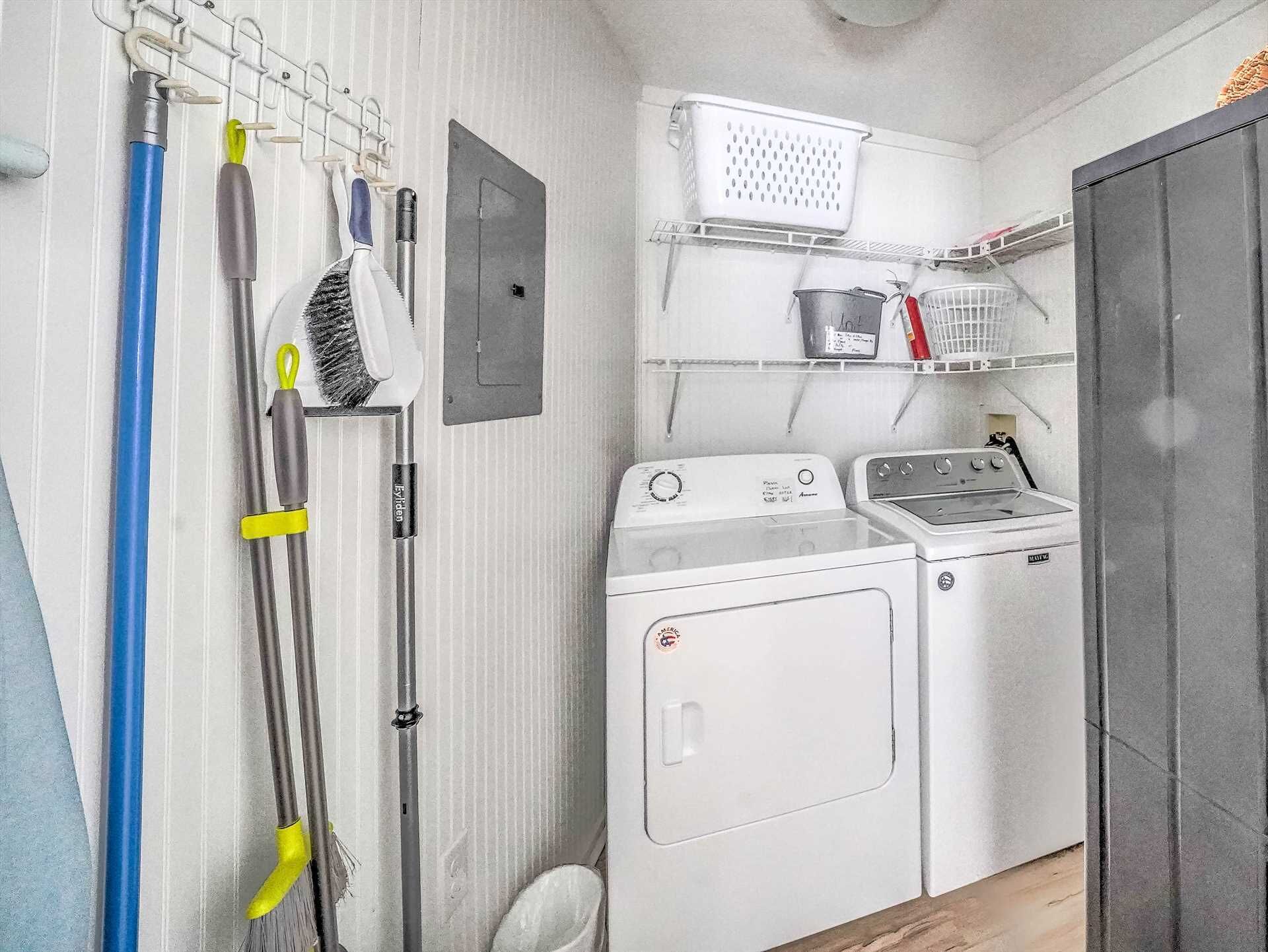A laundry room with a washing machine, dryer, and hanging laundry tools.