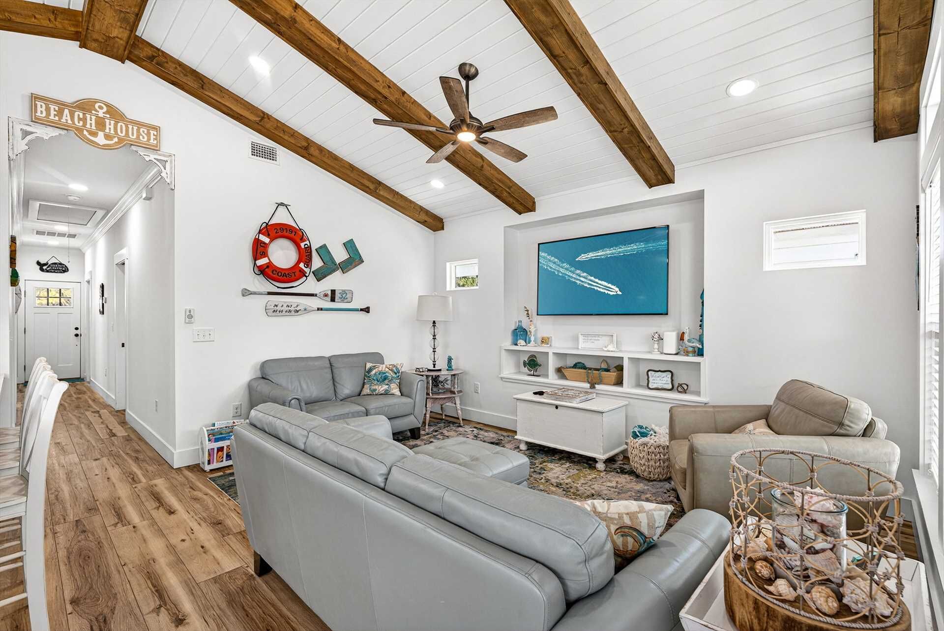 A beach-themed living room with a sectional sofa, a television, and nautical decor.