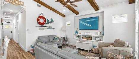 A beach-themed living room with a sectional sofa, a television, and nautical decor.